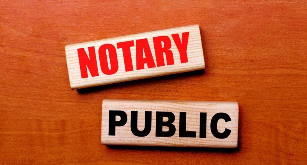 On a wooden table are two wooden blocks with the text NOTARY PUBLIC